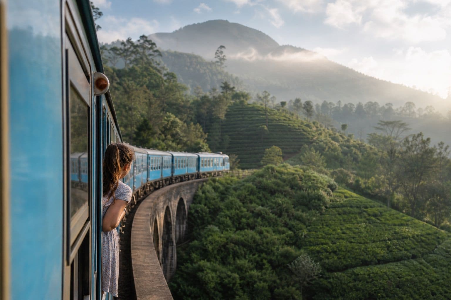 Hill country blue train crossing misty tea mountains in Sri Lanka