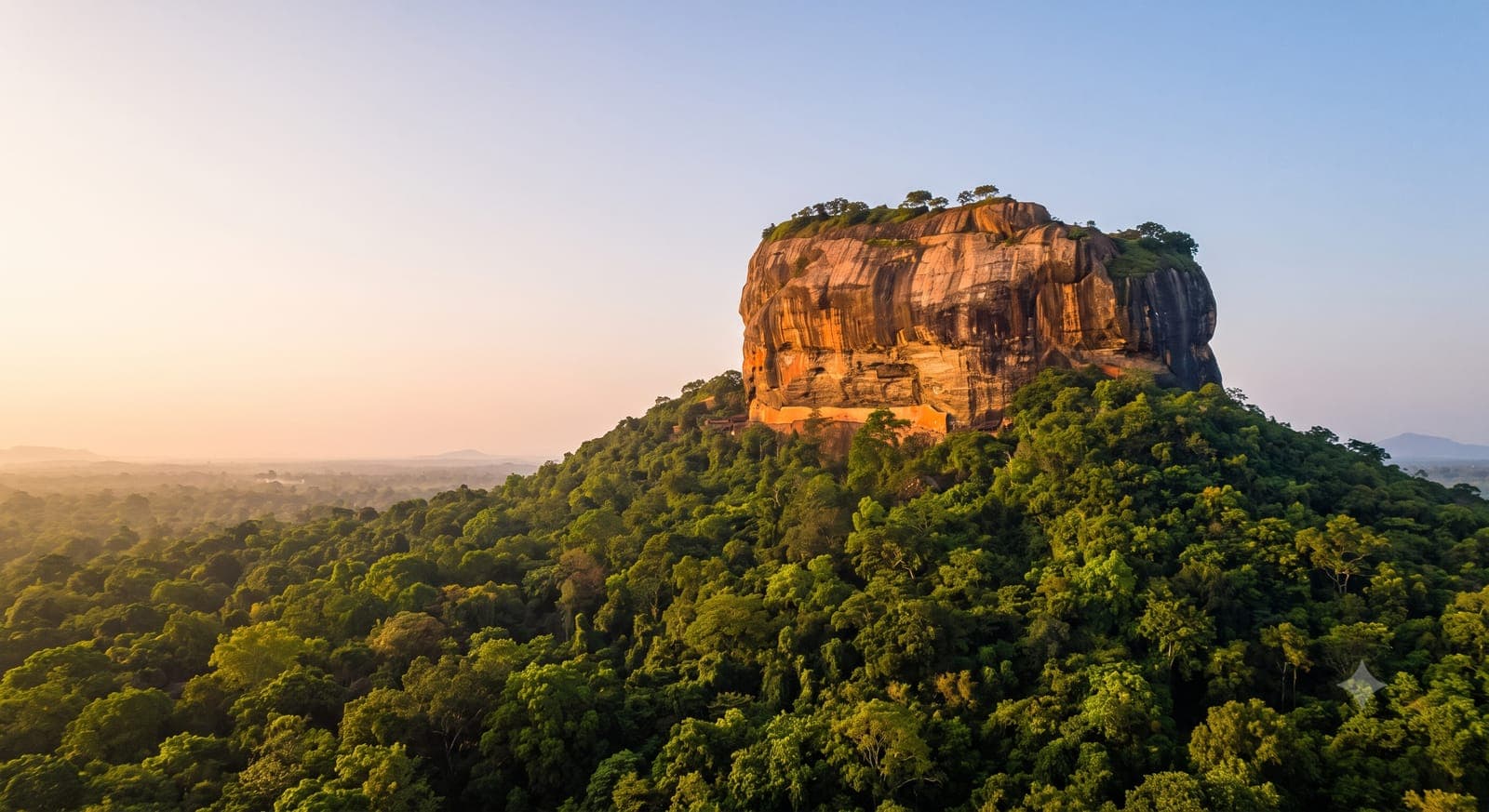 Sigiriya Rock Fortress rising from jungle canopy in soft early-morning light