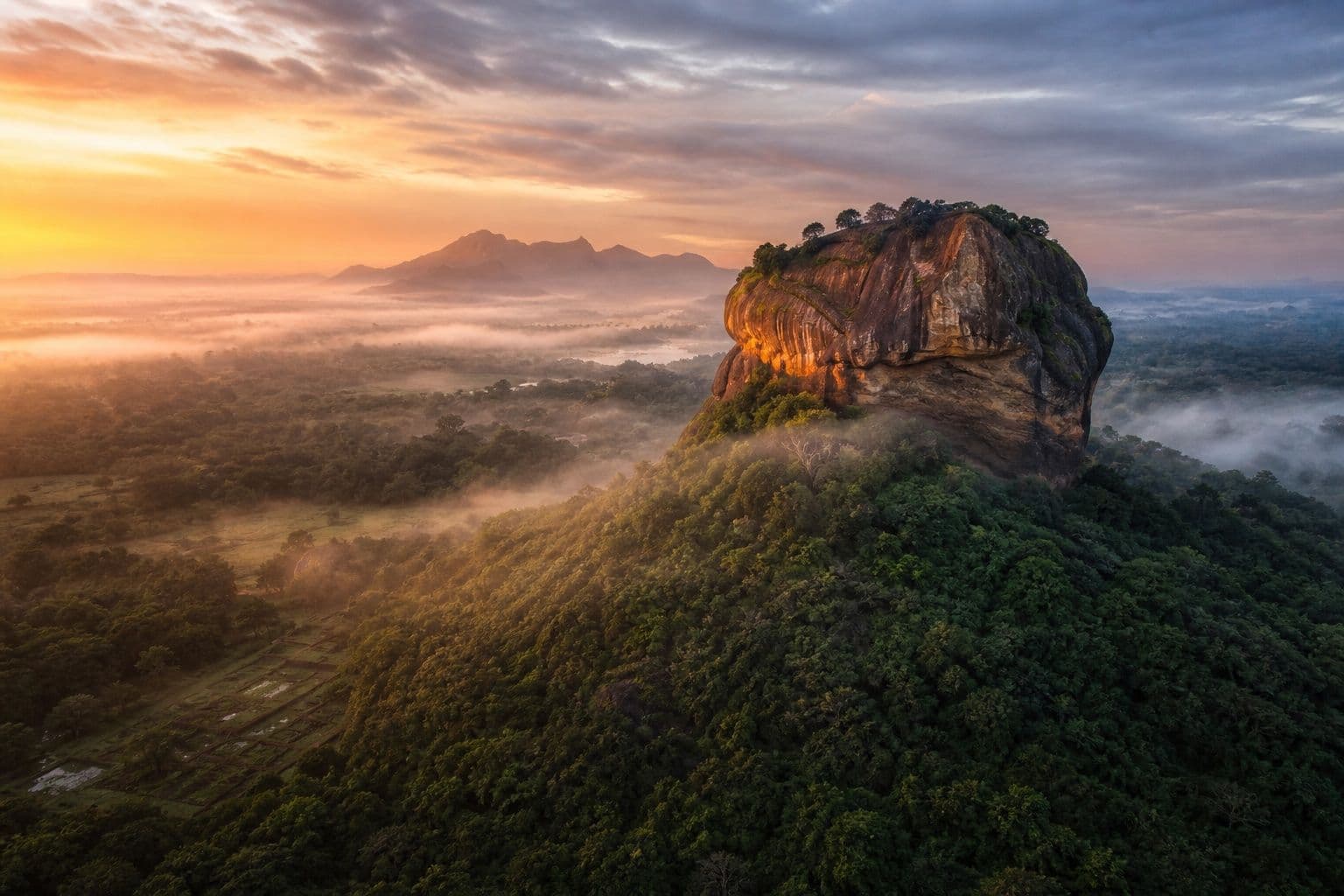 Sigiriya Rock Fortress rising above jungle mist at dawn